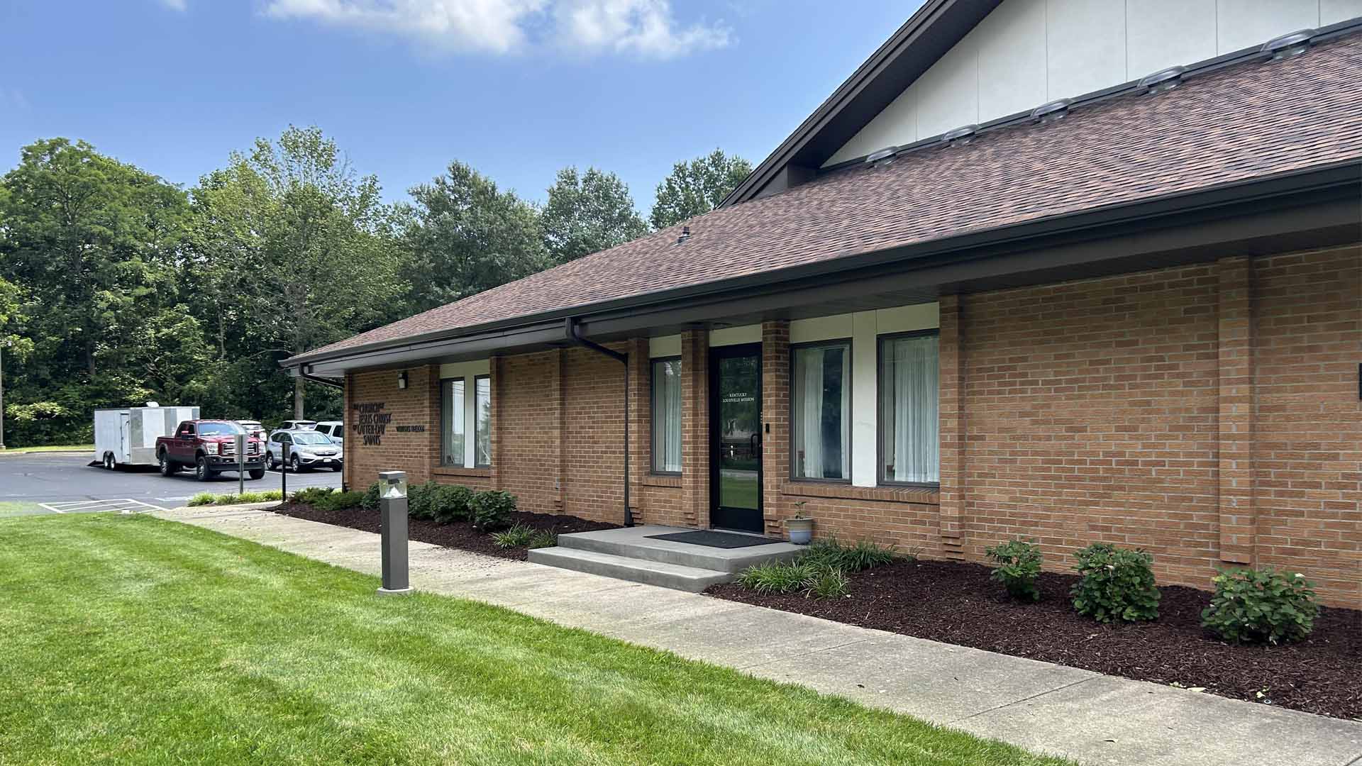 Astonishing landscaping service expertly arranged plants line brick building, premium mulch enhances breathtaking setting, vehicles visible.