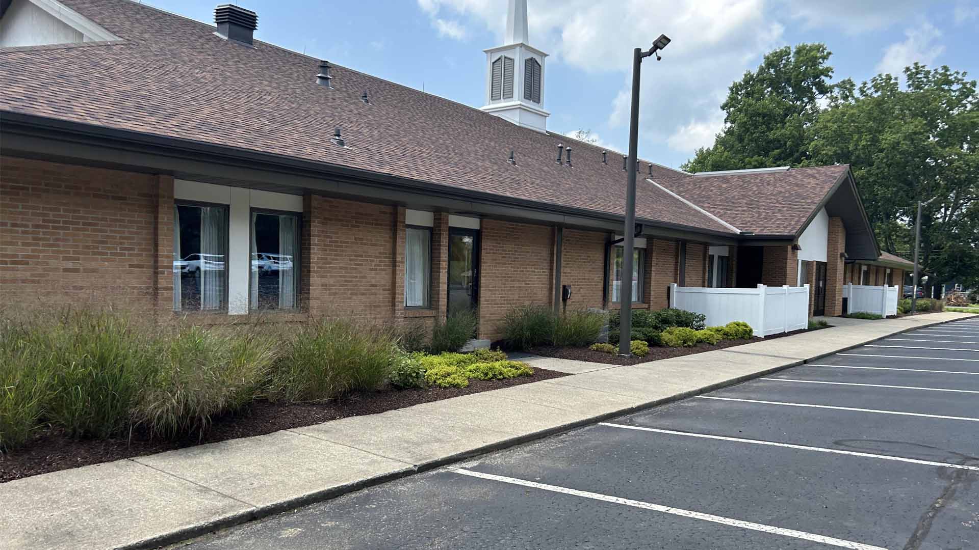 Amazing landscaping expertly designed beds frame brick building, dark mulch accents stunning grounds.